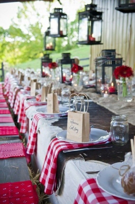 the tables are set with red and white checkered tablecloths, place settings, and candles