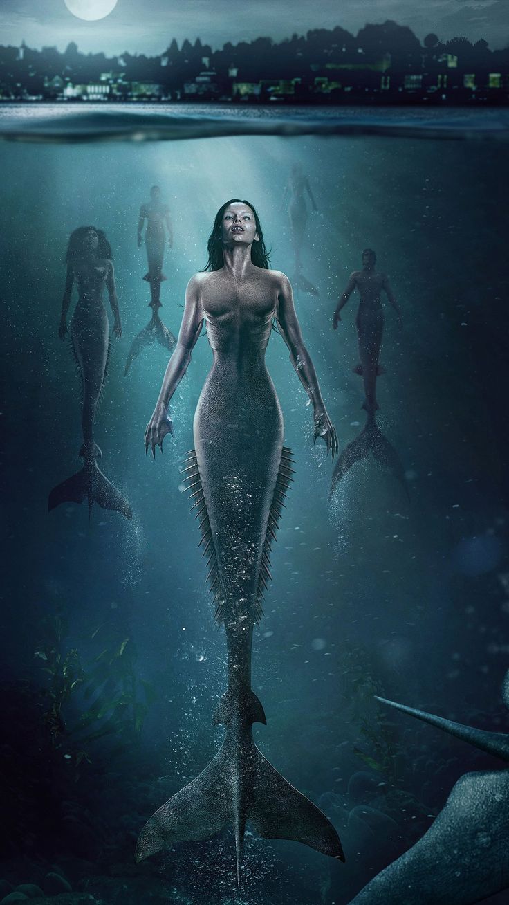 a woman is standing in the water surrounded by other people and fish, with one person swimming