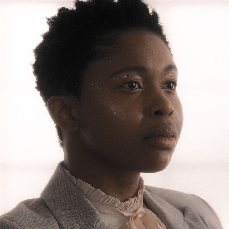 a woman in a suit and tie looking off to the side with her eyes closed