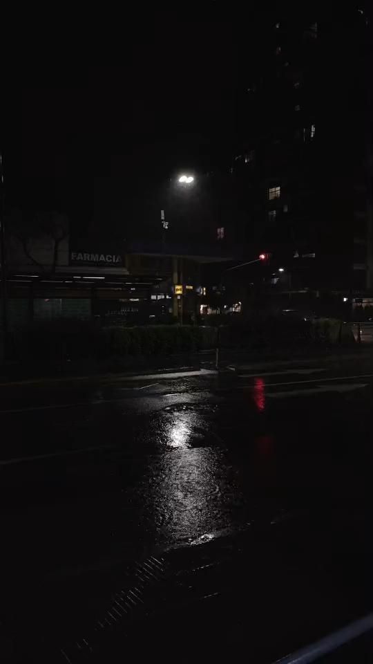 a street at night with the lights on and buildings lit up in the dark behind it