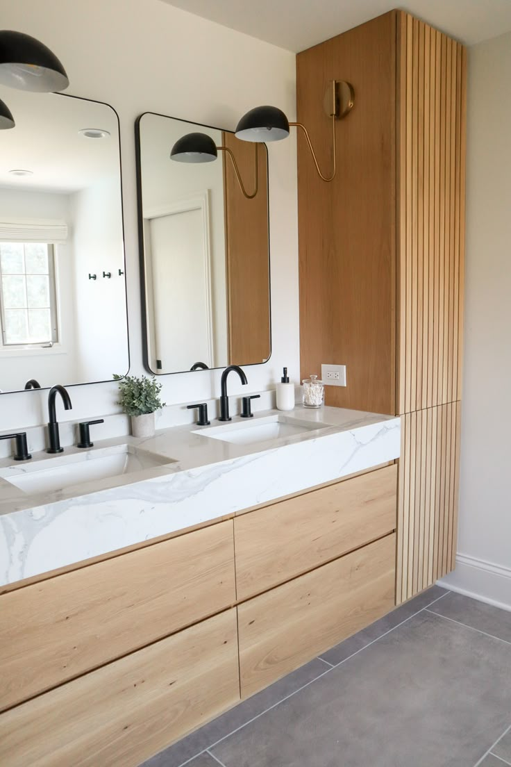 a bathroom with two sinks, mirrors and lights on the wall above them is shown