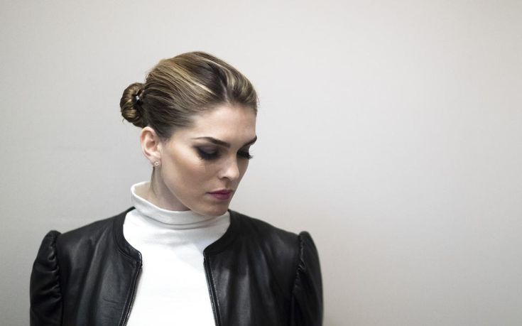 a woman wearing a black leather jacket and white turtle neck top with her hair in a bun