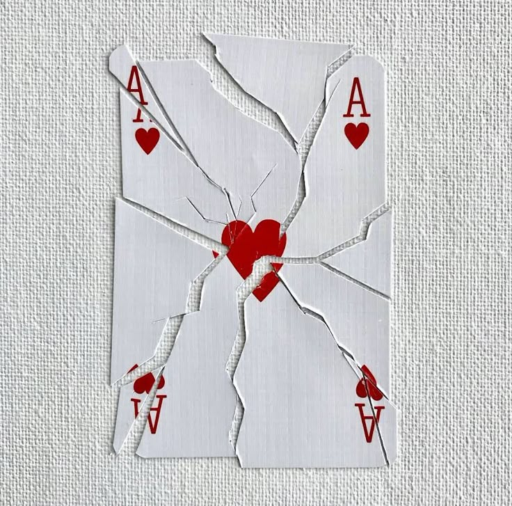 a broken playing card with hearts and arrows on the back is cut out to look like a spider