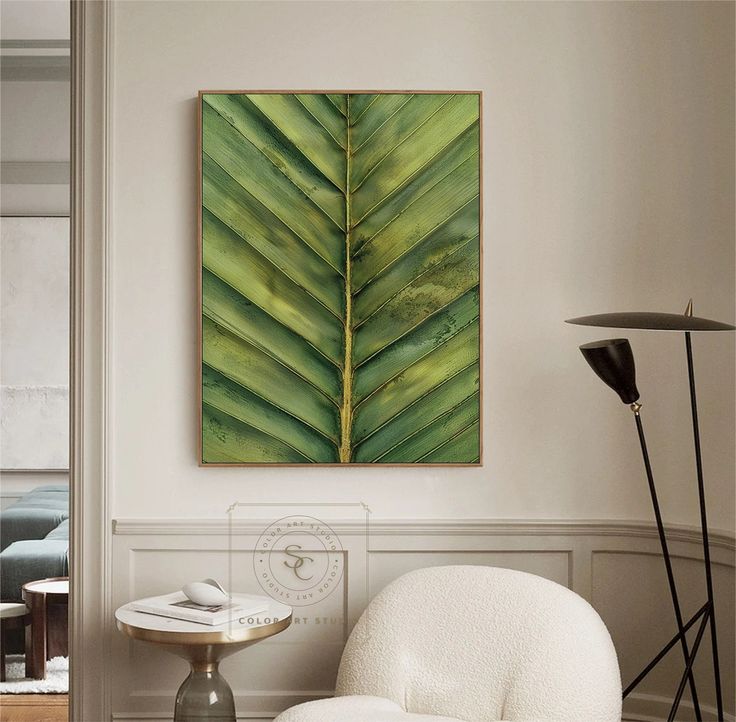 a living room with a white chair and a large green leaf on the wall above it