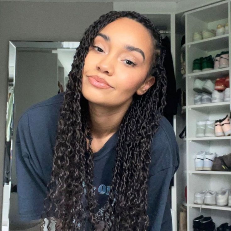 a woman with long curly hair standing in front of a closet filled with shoes and other items