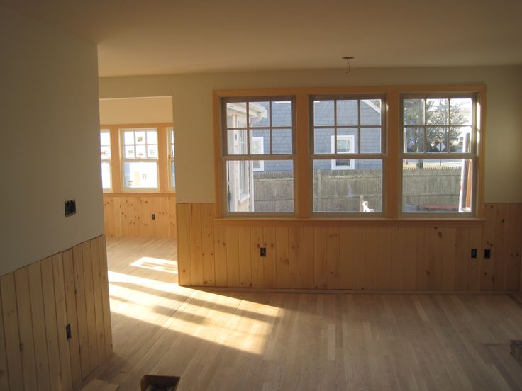 an empty room with wood paneling and windows