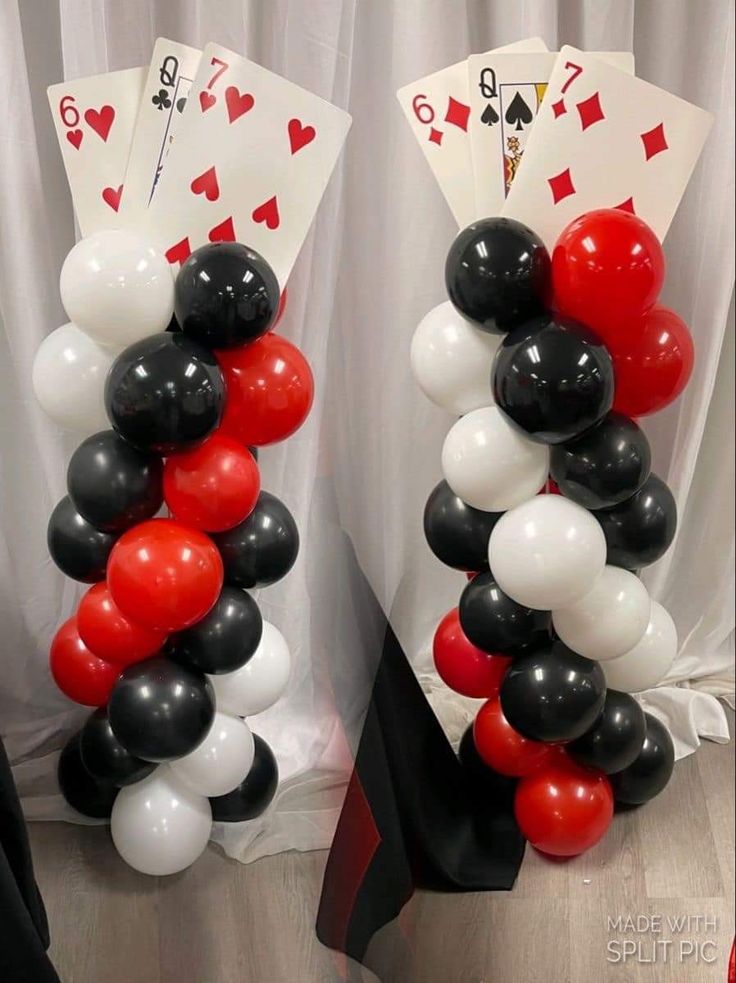 two stacks of cards and balloons in front of a white curtain with red and black playing cards