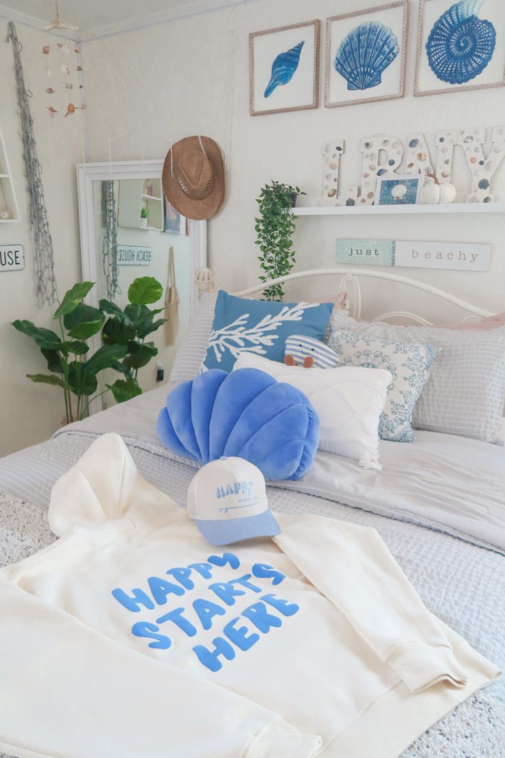 a white bed topped with blue pillows next to a hat and t - shirt on top of it