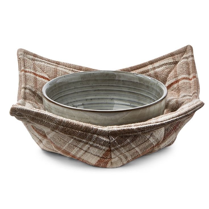 a metal bowl sitting on top of a plaid cloth covered dish holder in the shape of a rectangle