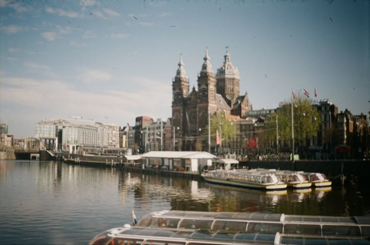 boats are docked on the water in front of large buildings with spires and towers