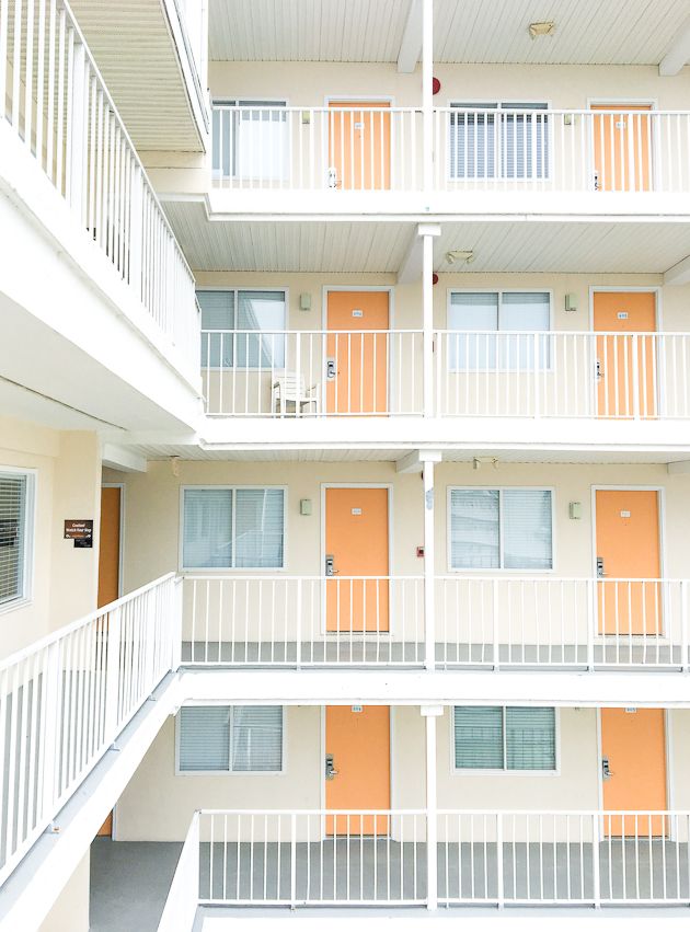 an orange and white apartment building with balconies on the second floor, looking down