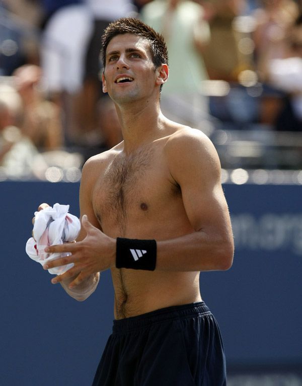 a shirtless man holding a tennis racquet on a court