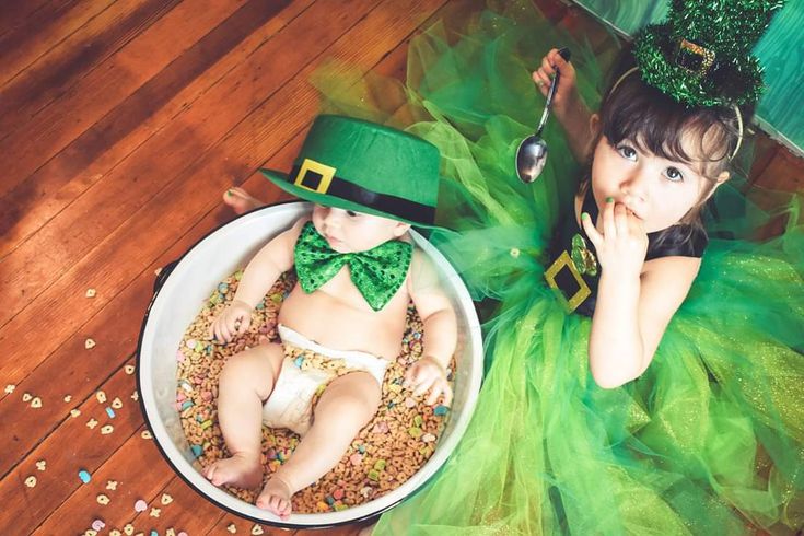 a baby in a st patrick's day outfit sitting next to a bowl of cereal