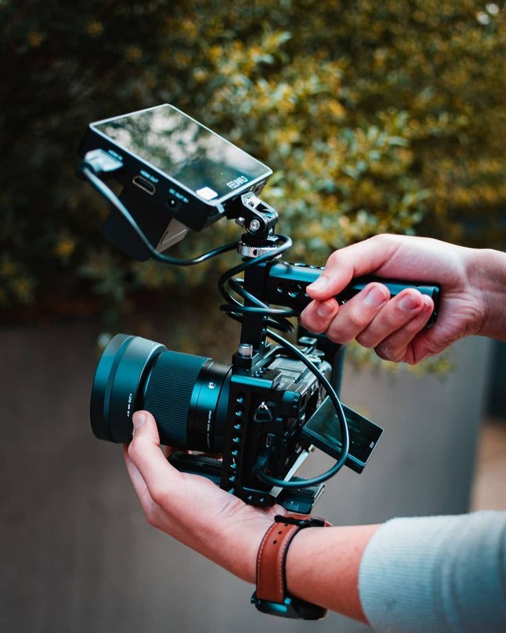 a person holding a camera in their hand with the other hand on top of it