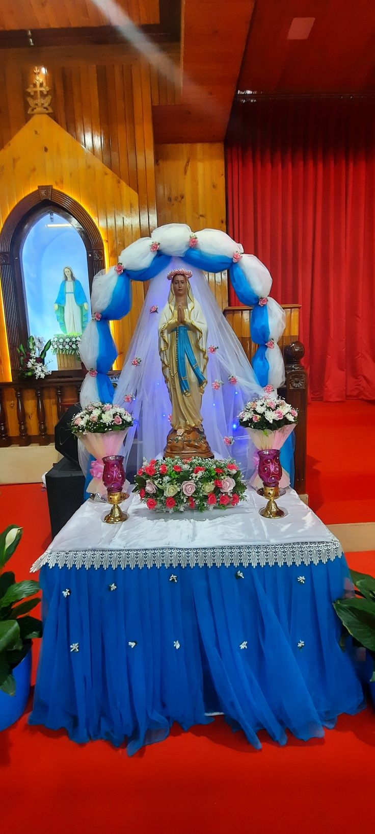 an altar decorated with blue and white cloths, flowers and decorations on the table