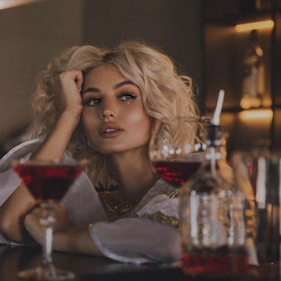 a woman sitting at a bar with two glasses of wine in front of her,