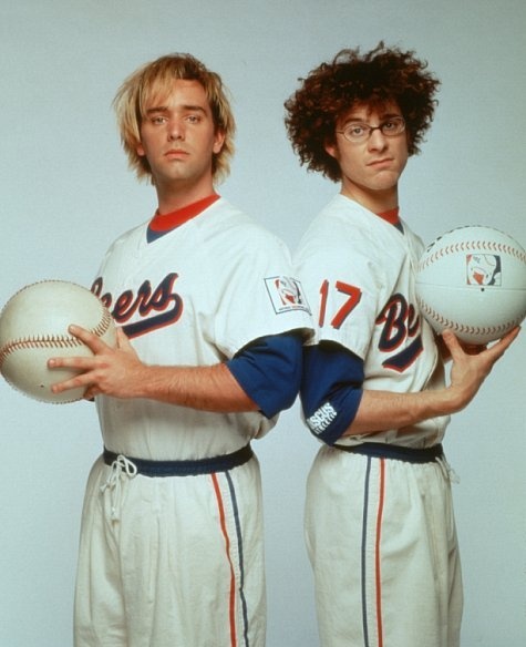 two baseball players are posing for a photo with their balls in their hands and one has curly hair on his head