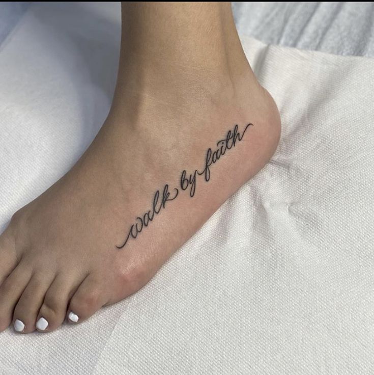 a woman's foot with the words walk by faith tattooed on her left side