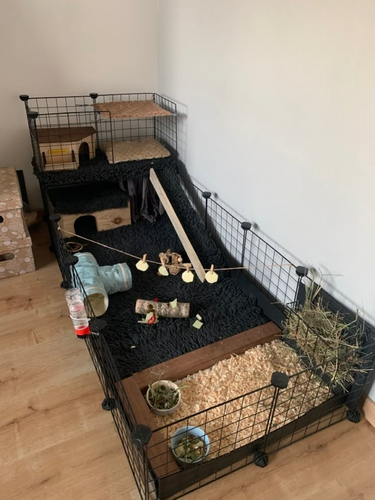 two cages with food and other items in them on the floor next to a wall