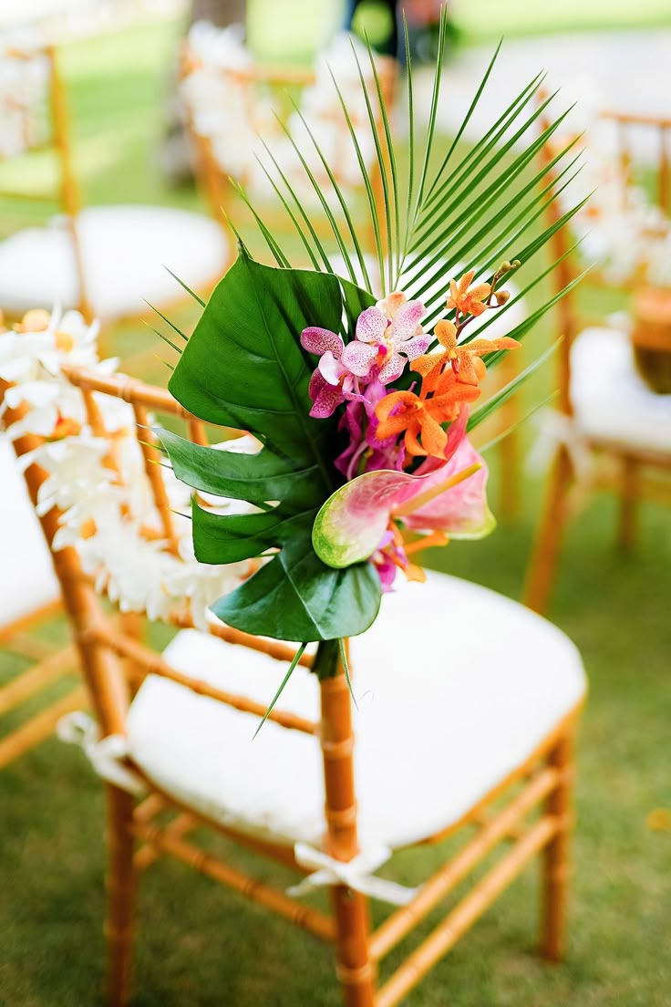 the chairs are decorated with tropical flowers and greenery