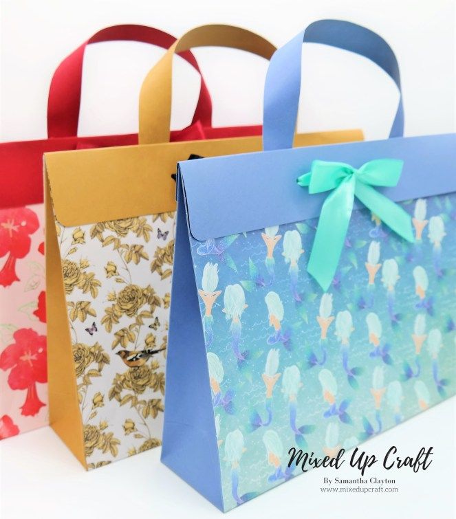 three bags with bows on them sitting side by side in front of a white background