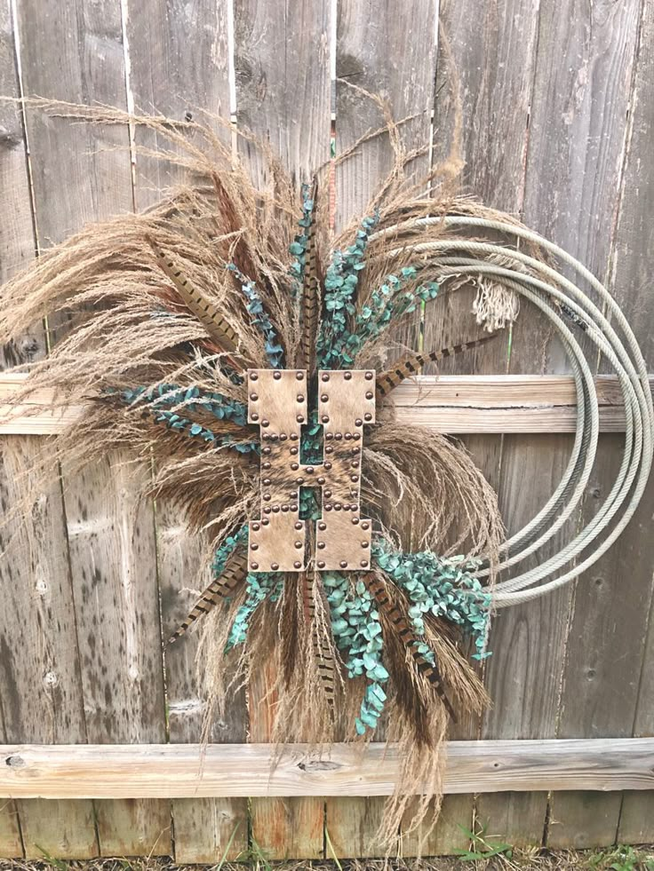 a wreath made out of dried grass sitting on top of a wooden fence