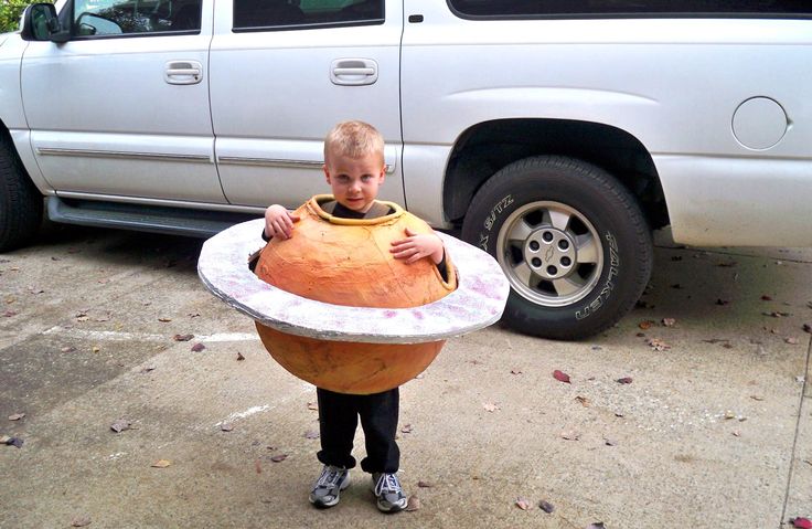 a man holding a large round object in front of a white truck on the street