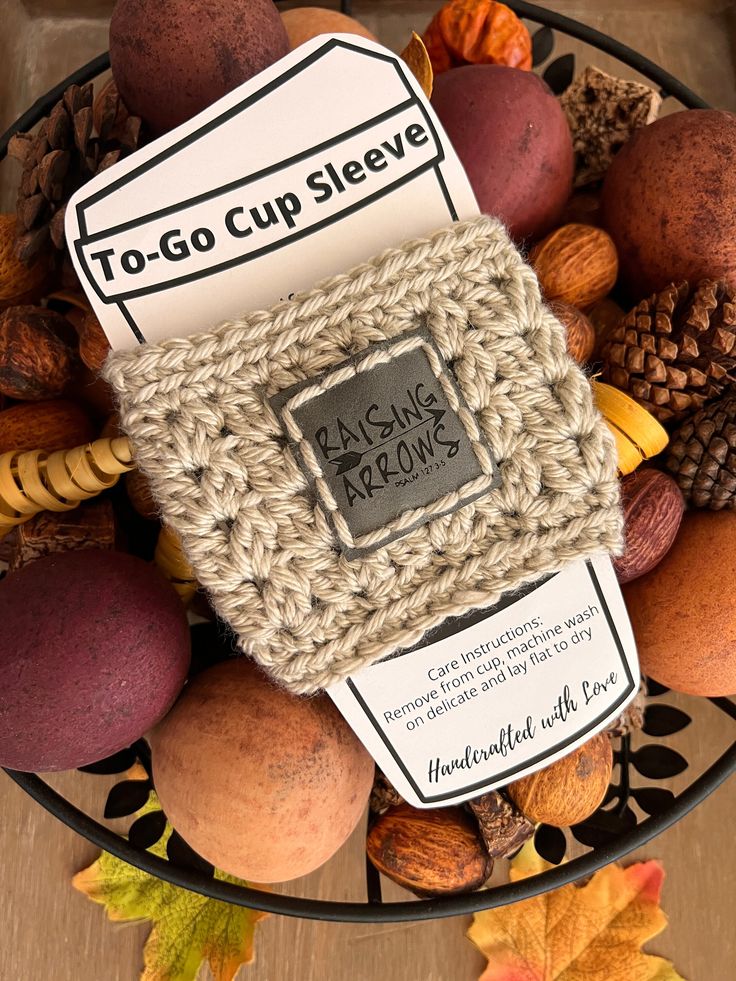 a bowl filled with nuts and acorns on top of a wooden table next to a sign that reads, to go cup sleeve