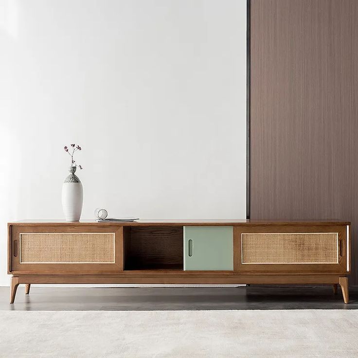 a vase with flowers is on top of a wooden entertainment center in an empty room