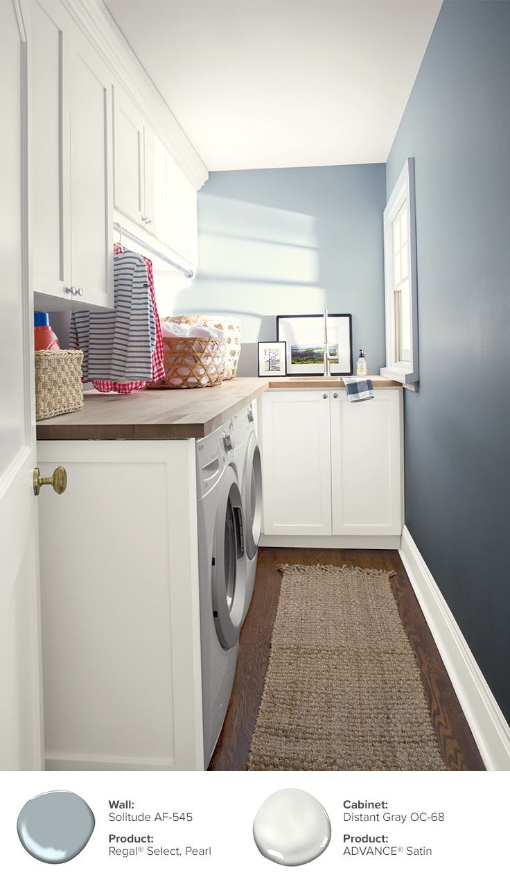 a laundry room with blue walls and white cabinets