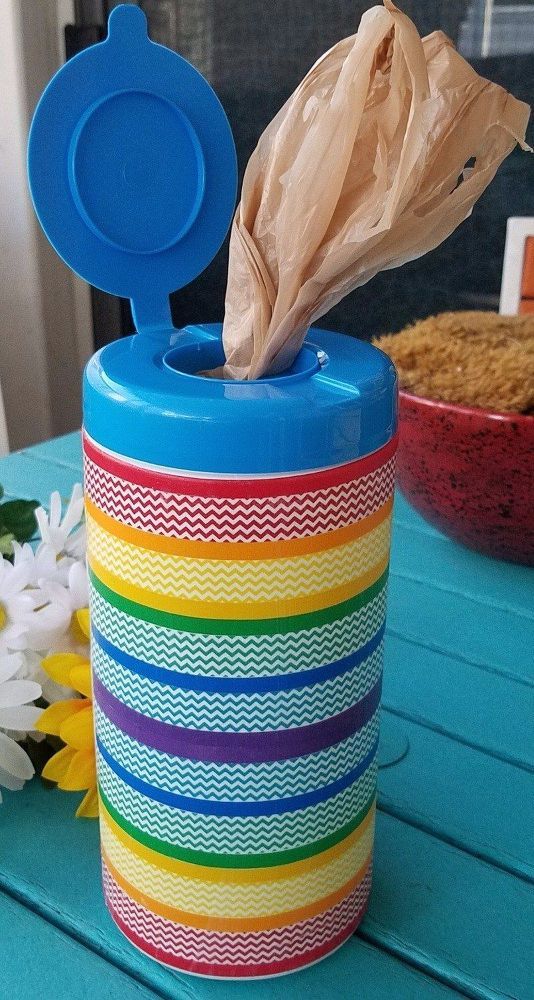 a colorful container with tissue paper in it on a table next to a bowl and flowers