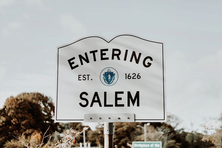 a white sign that reads entering salem on it's side in front of some trees