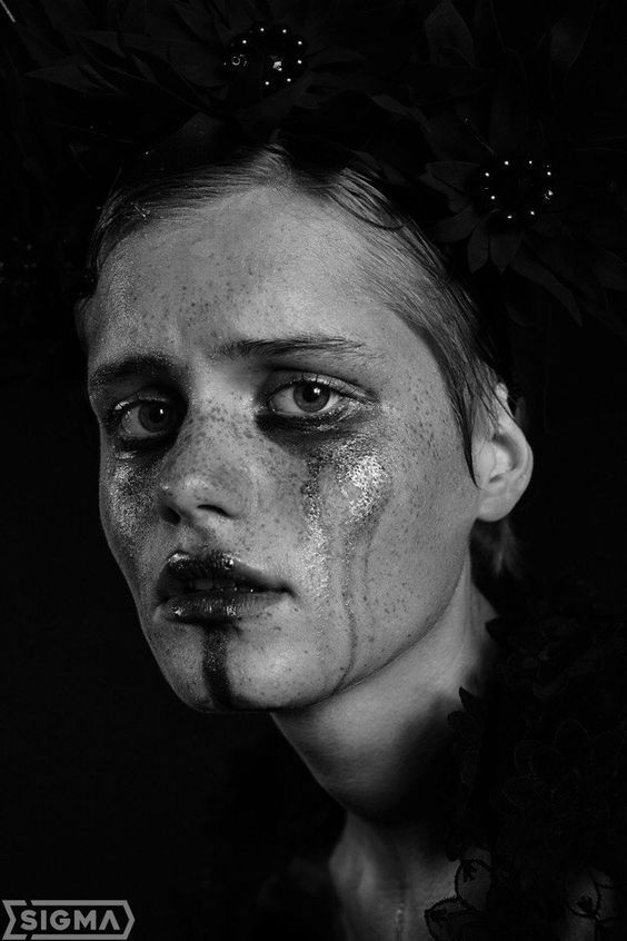 a black and white photo of a woman with freckles on her face, wearing makeup