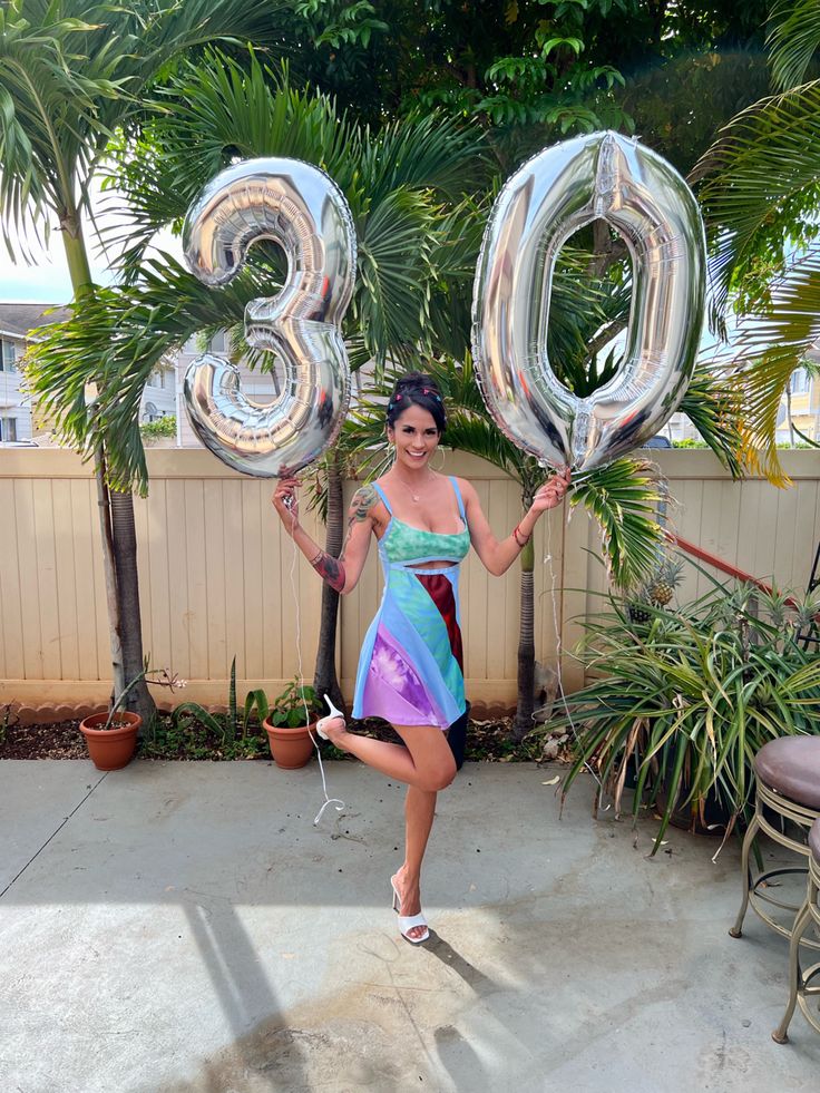 a woman is holding two large balloons in front of her and posing for the camera