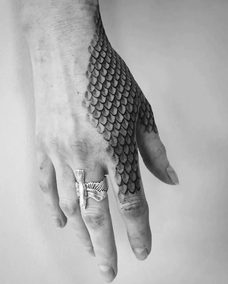 a man's hand with a ring on it and a snake skin design on the middle finger