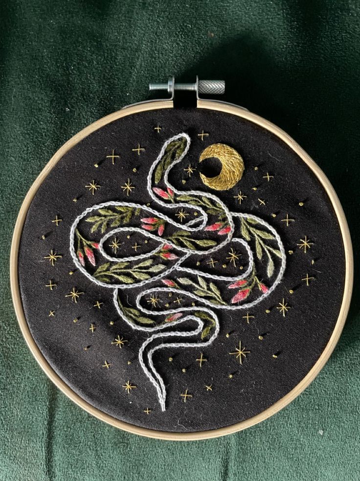 a black and gold embroidered hoop with a snake on it