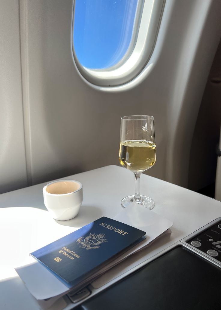 a glass of wine and passport on an airplane