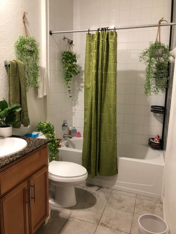 a bathroom with a shower, toilet and bathtub covered in green curtained curtains