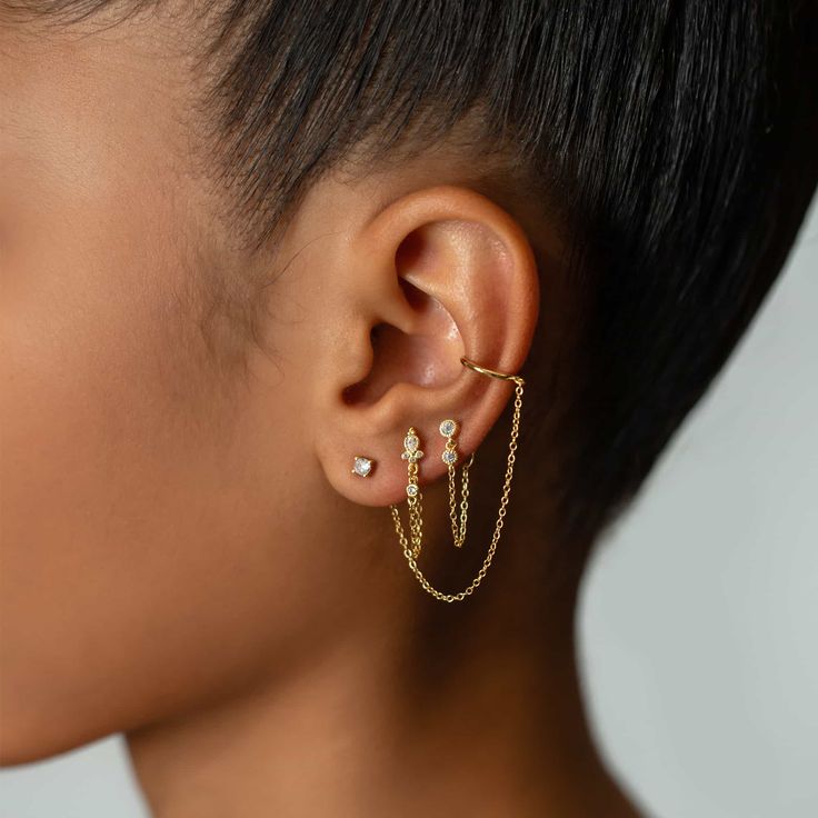 a close up of a person wearing gold ear cuffs with chain attached to the ears