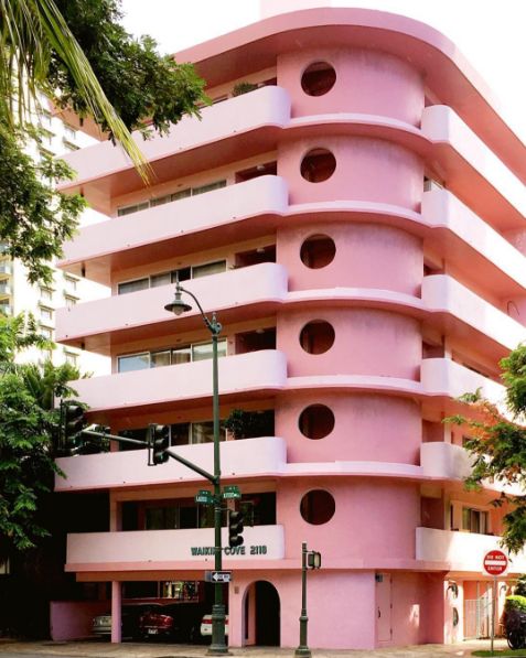 a tall pink building sitting on the side of a road