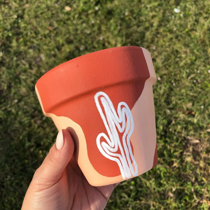 a person holding up a cup with a sticker on it's side in the grass