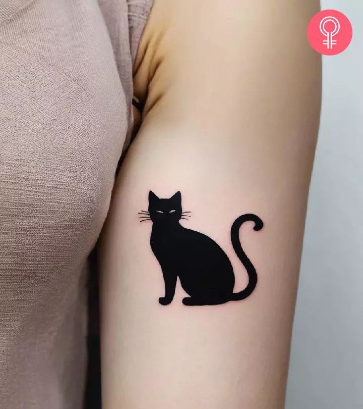 a black cat tattoo on the arm