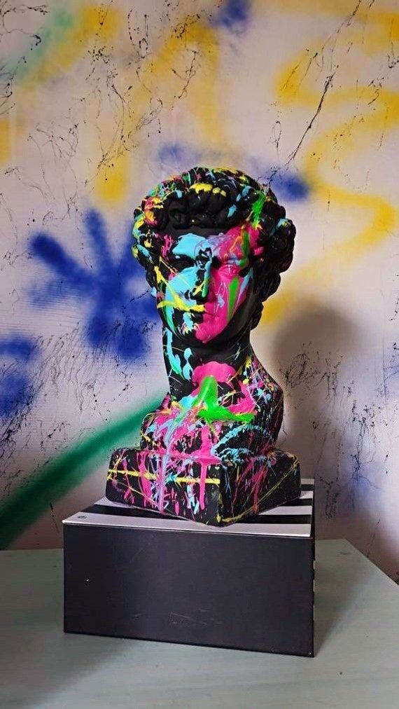 a black and white sculpture with colorful paint splattered on it's face