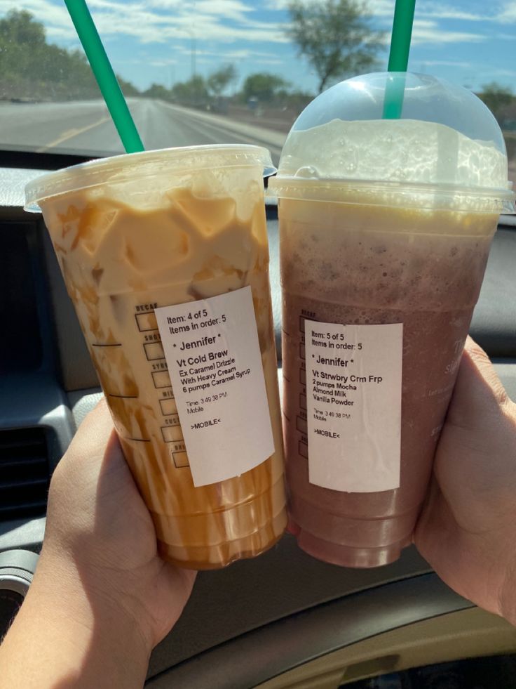 two drinks are being held up in the car