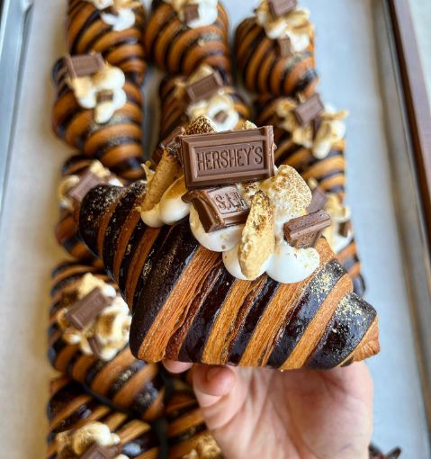 a person holding up a piece of chocolate covered pastry