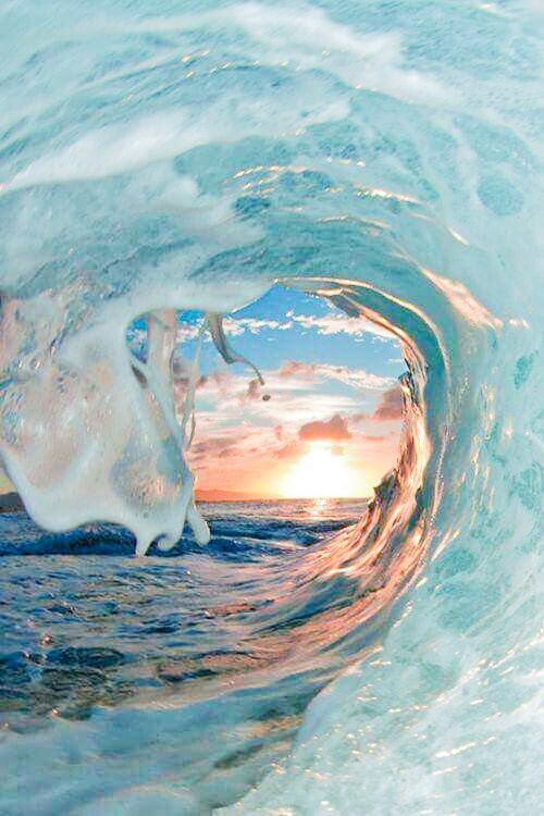 an ocean wave with the sun setting in the background and some water swirling around it