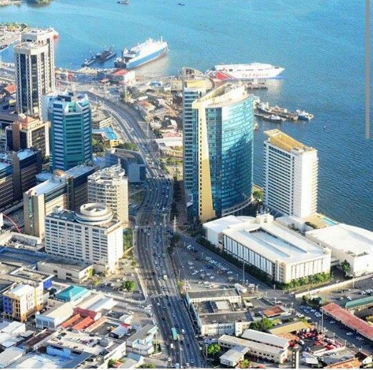 an aerial view of a city with tall buildings in the foreground and a large body of water behind it