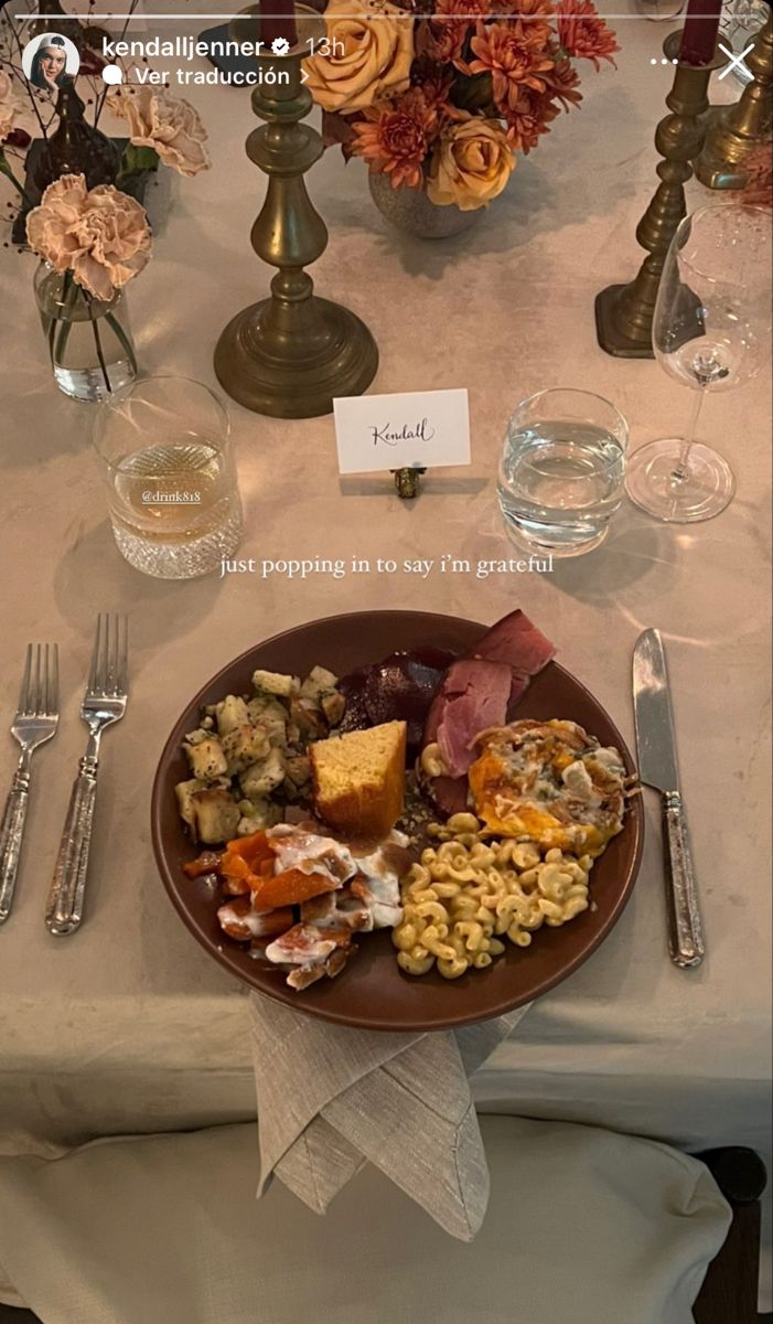 a plate of food on a table with silverware and flowers in vases behind it