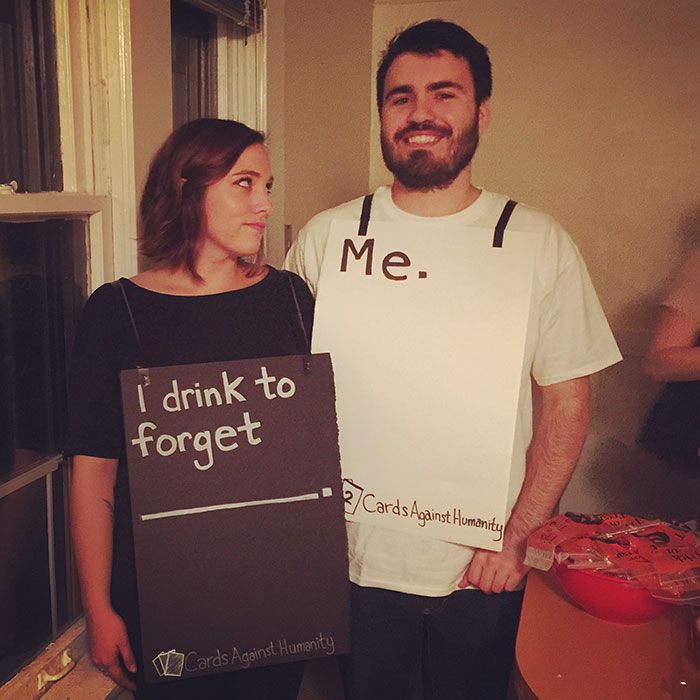 a man and woman standing next to each other holding signs that say i drink to forget