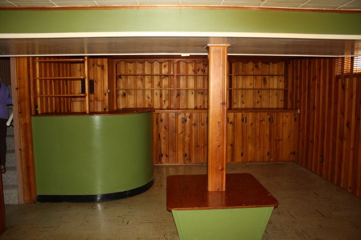 an empty room with wood paneling and green counters